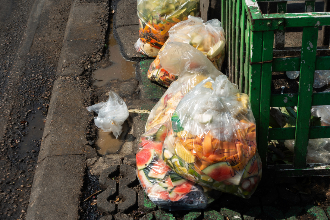 Food waste in plastic bags on footpath